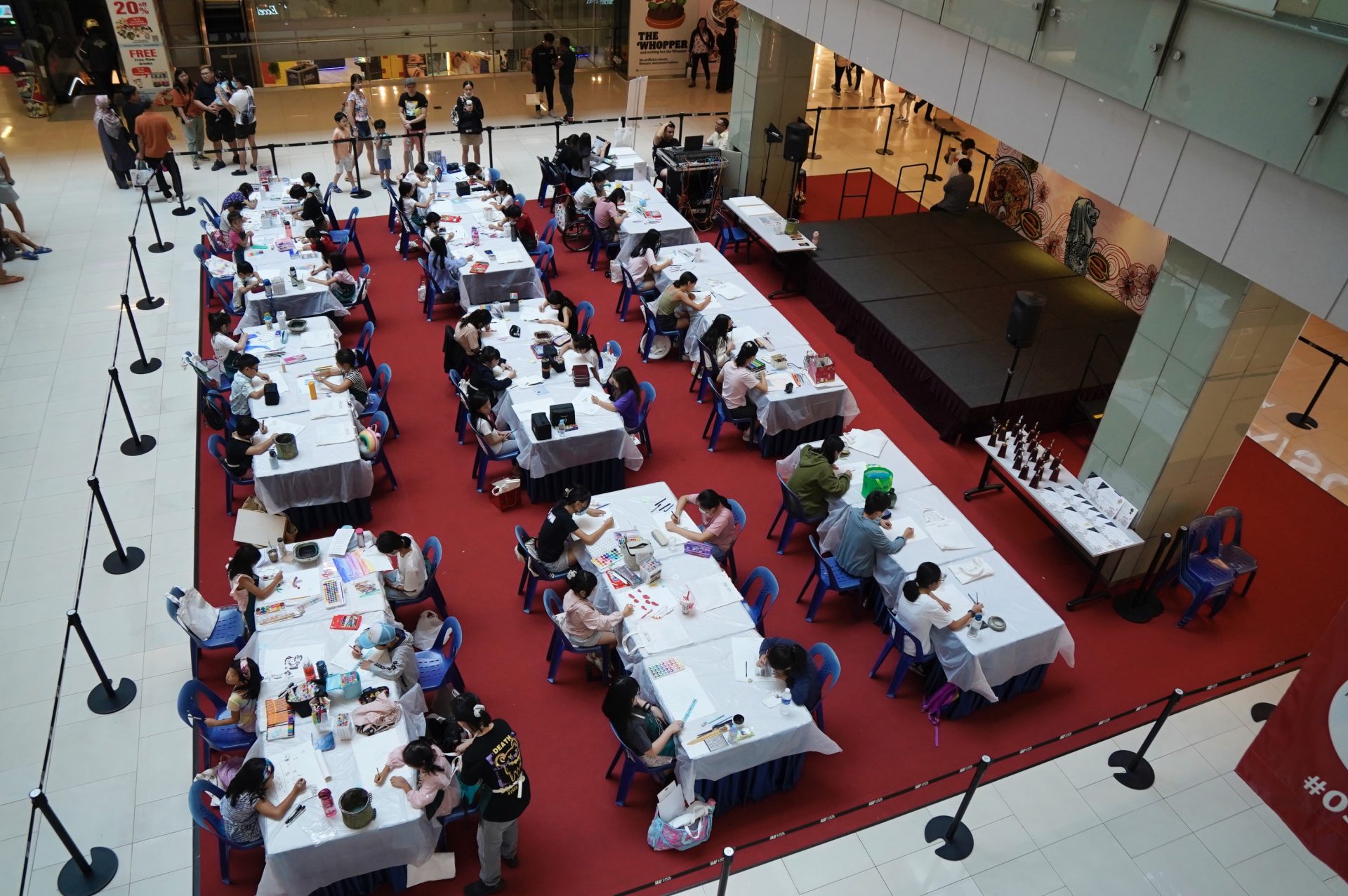 Overhead view of rows of competition tables filled with young artists at the Kine x CultuRediscover competition