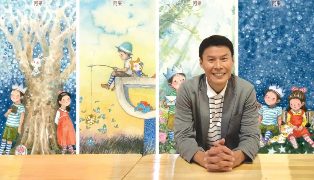 Mr Kow Fong smiling in front of a backdrop of his own children's book illustrations