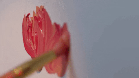 Close-up of a paintbrush applying red petals to a flower painting