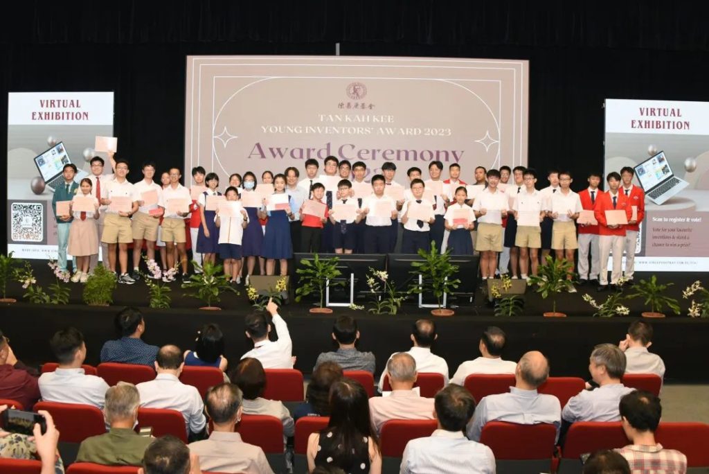 Student award winners holding certificates on stage at the Tan Kah Kee Young Inventors' Award Ceremony 2023