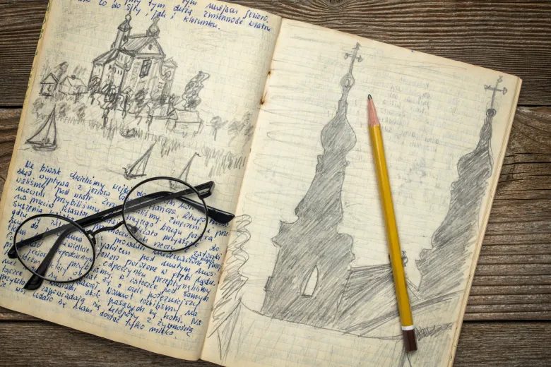 An open art journal filled with pencil sketches, with a pair of glasses and a pencil resting on its pages