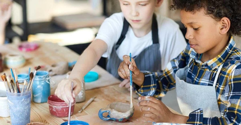 An instructor supervising children during a group art class activity