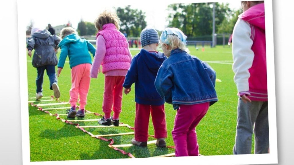 Group of children walking together along an outdoor rope ladder game, practicing teamwork
