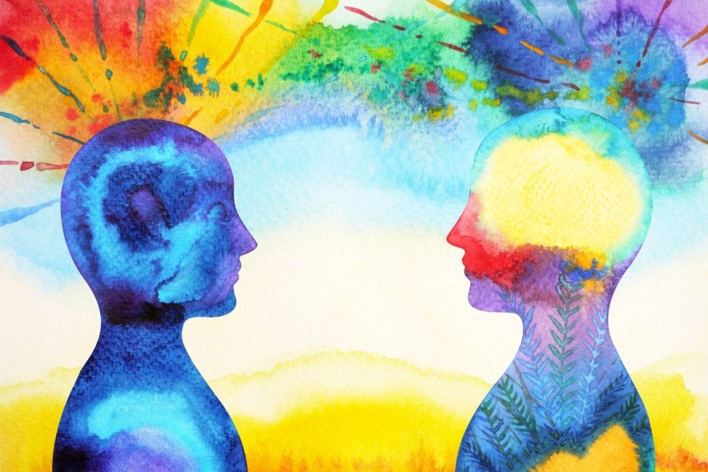 Watercolour illustration of two colourful silhouetted heads facing each other with bursts of paint above them, symbolising thoughts and emotions