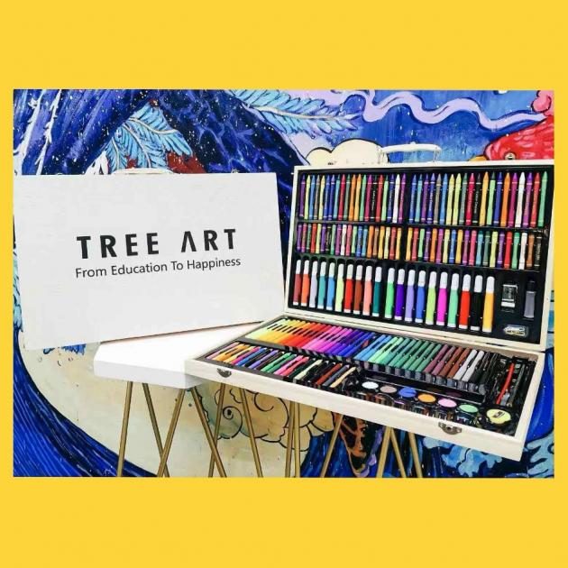 Wooden art supply case filled with crayons, pastels and markers beside a Tree Art easel sign reading "From Education To Happiness"