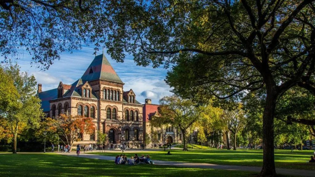 Ivy League campus scene with a Gothic-style academic building and students relaxing on the lawn