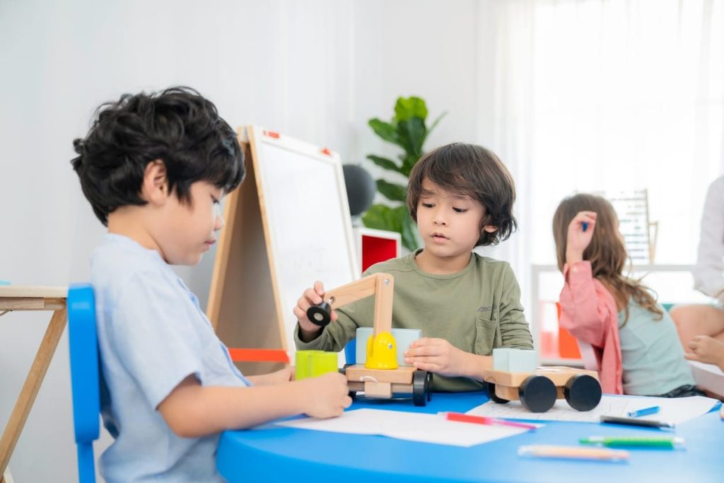 Children working together on a wooden craft project at a table