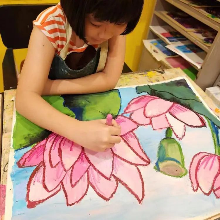 Child painting a pink lotus flower artwork in an art class