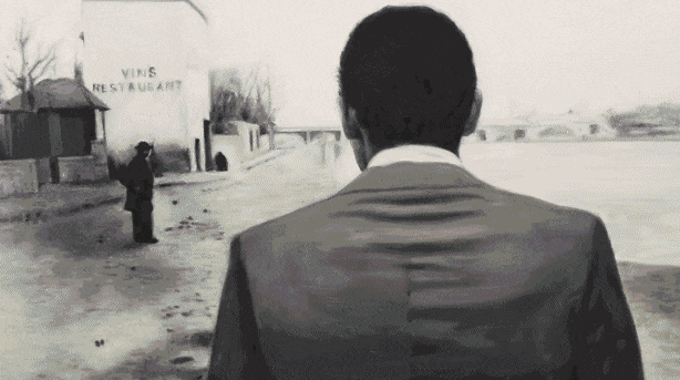 Black-and-white animated scene from Loving Vincent showing a figure walking through the riverside town where Van Gogh died