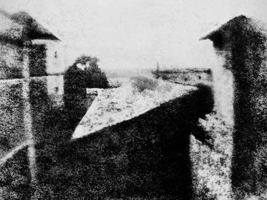 An early, grainy daguerreotype-era photograph of rooftops, illustrating the origins of photography