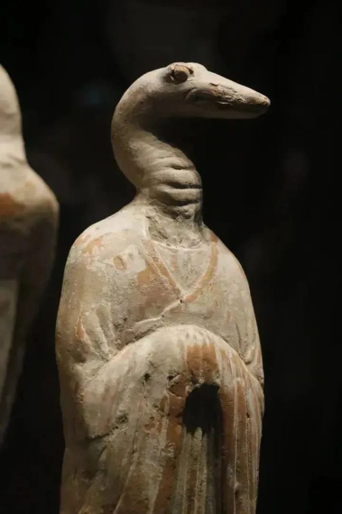 Tang dynasty terracotta zodiac tomb figurine with a snake-like head and a human body in flowing robes, from a museum display of the twelve zodiac generals
