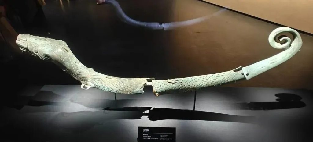 The Sanxingdui bronze snake, showing its slender segmented body, upraised head, wide round eyes, and detailed scale patterns