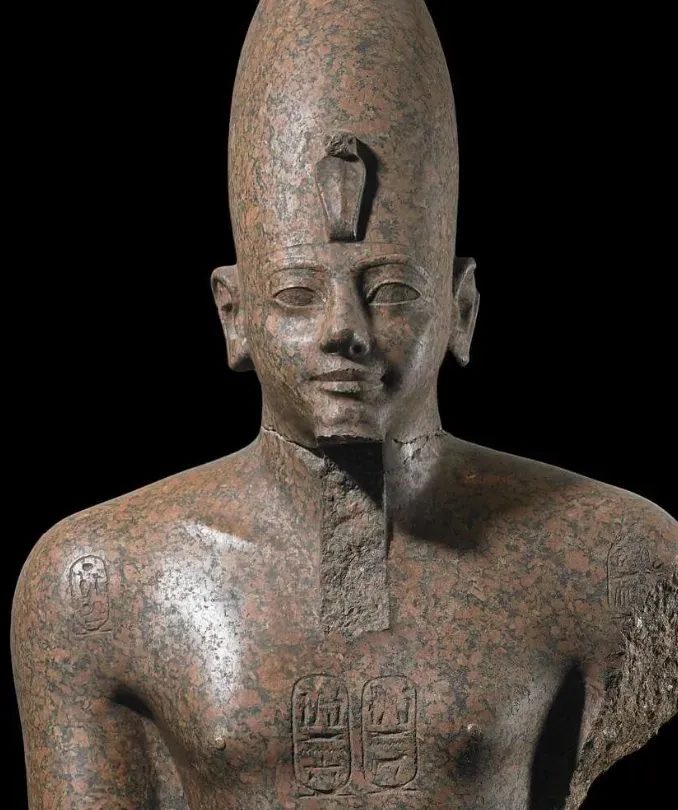 Statue of an ancient Egyptian pharaoh wearing a crown with the cobra uraeus emblem on the forehead, symbolizing royal protection