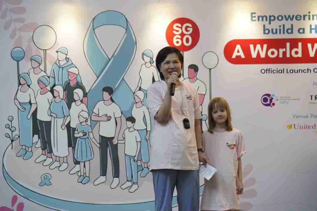 Eileen Dong speaks at the microphone alongside her daughter Pippi Alison Dong, sharing their story of giving back
