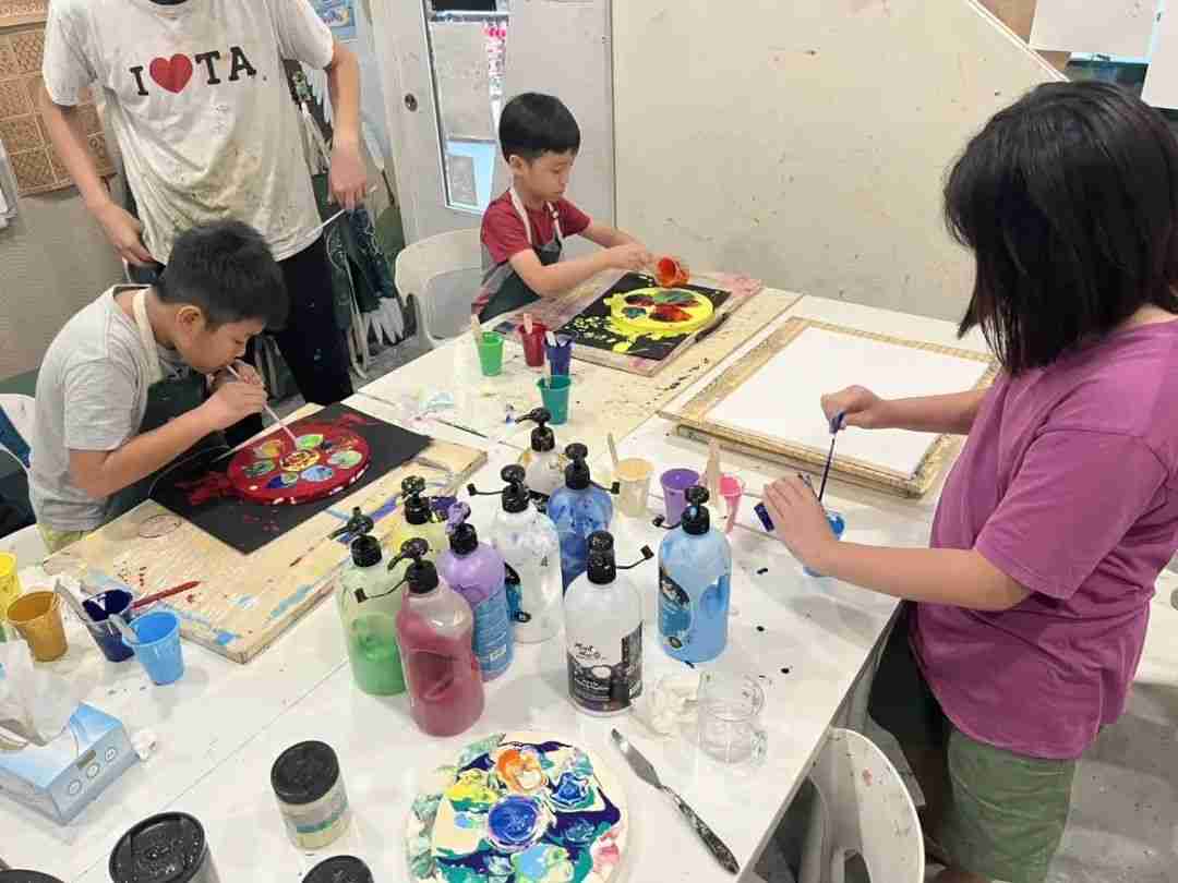 Children painting on round canvases with acrylic paints in the studio