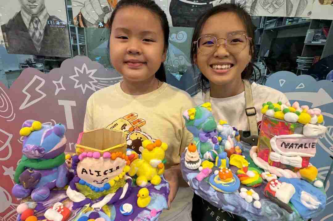 Two girls proudly showing their personalized clay sculptures