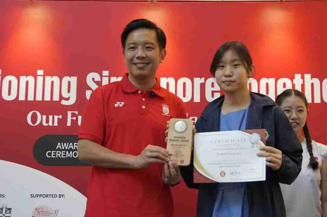 Mr Alvin Tan presenting an award plaque and certificate to a young winner at the Our Future Canvas awards ceremony