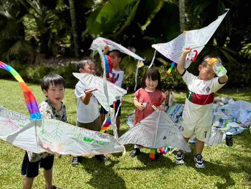 Children holding hand-painted kites they made outdoors