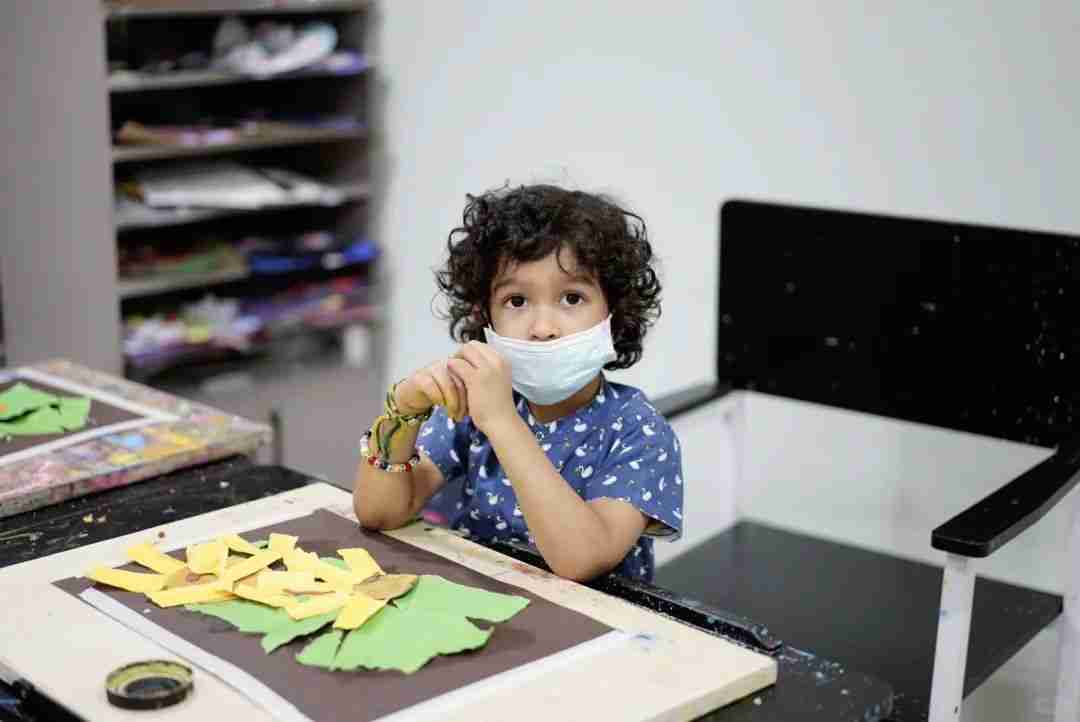 A young child creating a paper collage of sunflowers