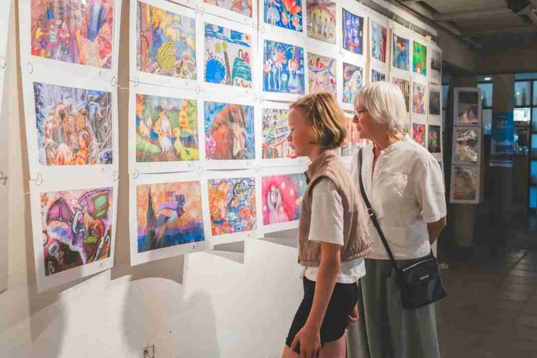 Visitors studying a wall of colourful children's artworks at the exhibition