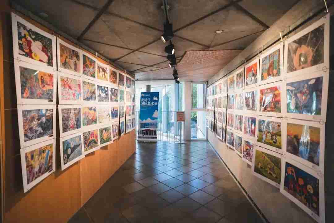 Gallery corridor lined with children's artworks under museum lighting in Odense