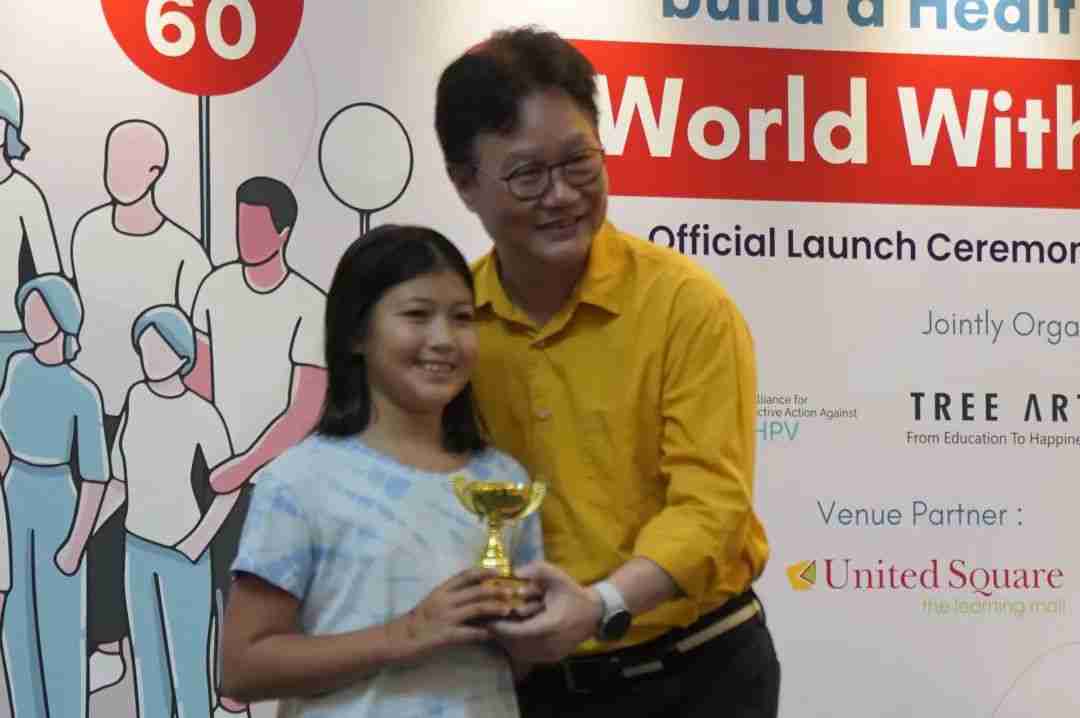 Mr Koh Juay Meng presenting a trophy to a smiling young winner at the award ceremony