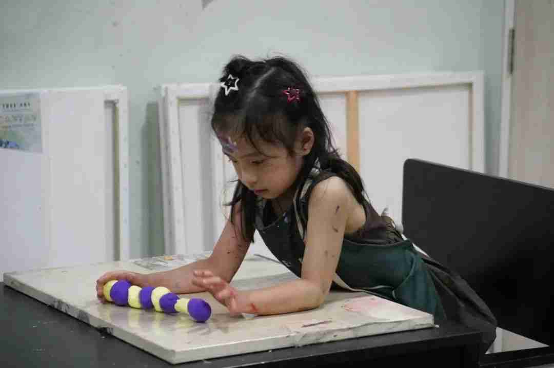 A child shaping colorful clay into a caterpillar figure