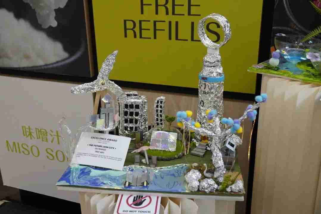 A foil-and-mixed-media sculpture titled The Future Lion City, envisioning a futuristic Singapore cityscape, tagged with an Excellence Award at the exhibition