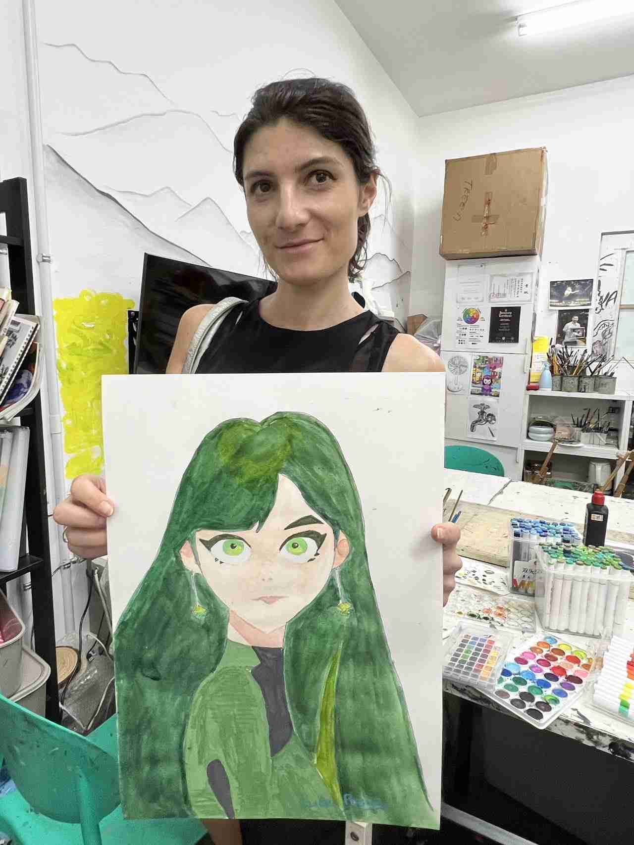 Adult student smiling and holding her finished portrait painting in the Tree Art studio