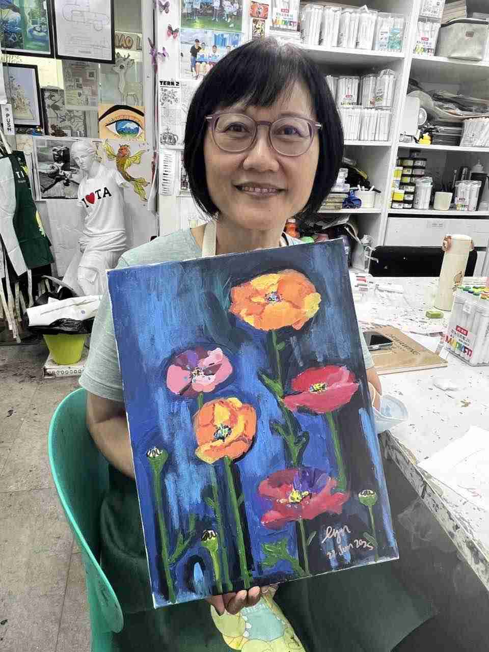 Senior artist holding her poppy still-life painting