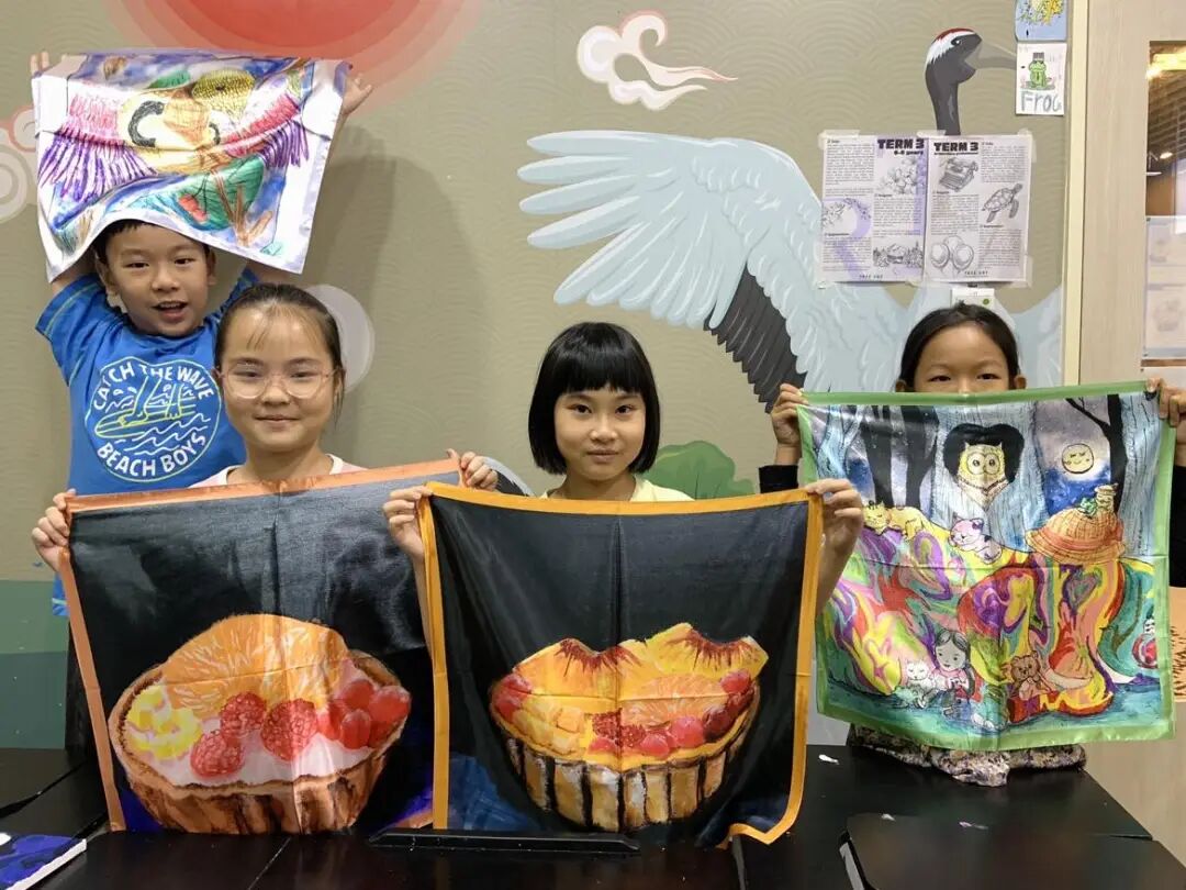 Child smiling while holding their silk scarf creation