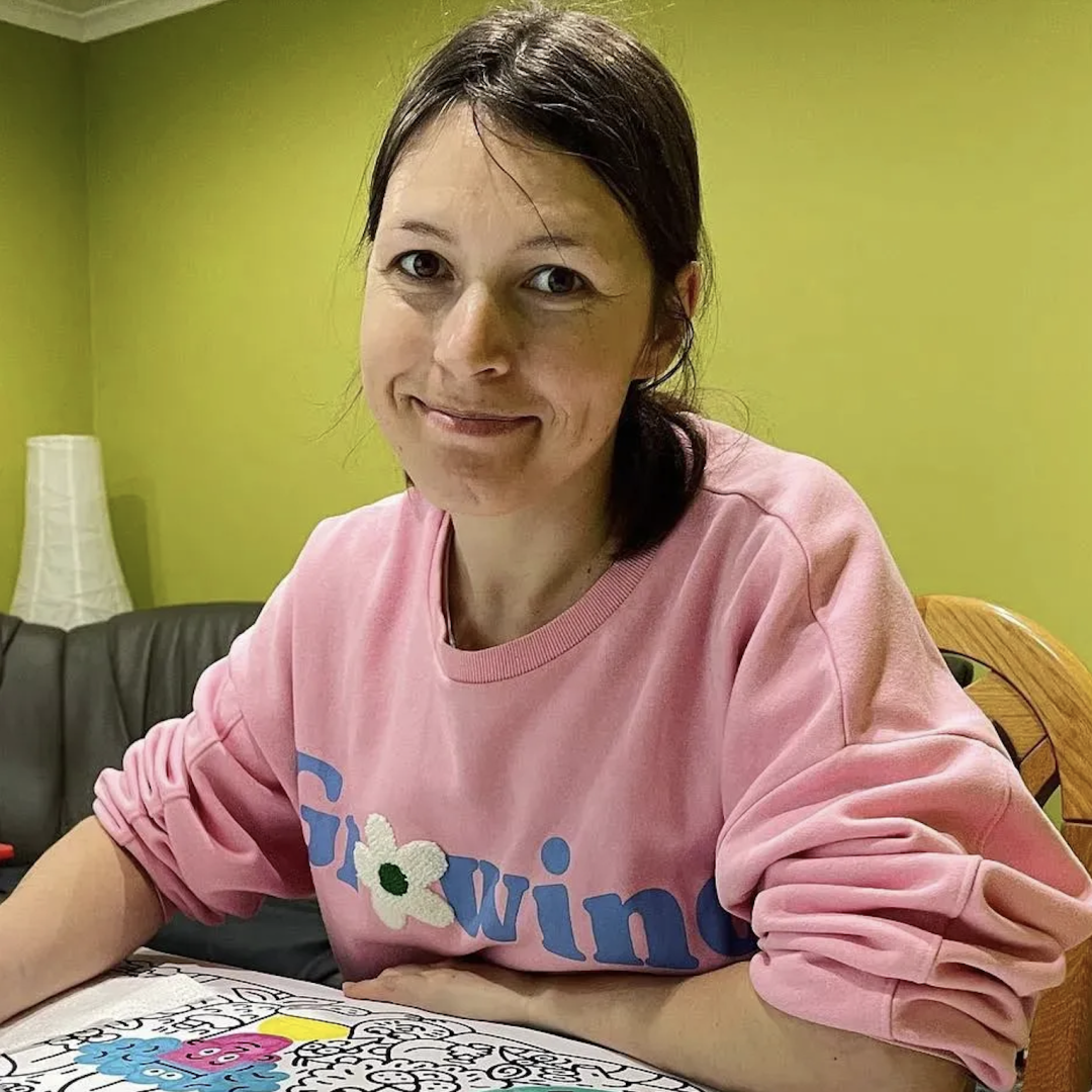Portrait of Ukrainian illustrator Nina Dzyvulska smiling at her worktable