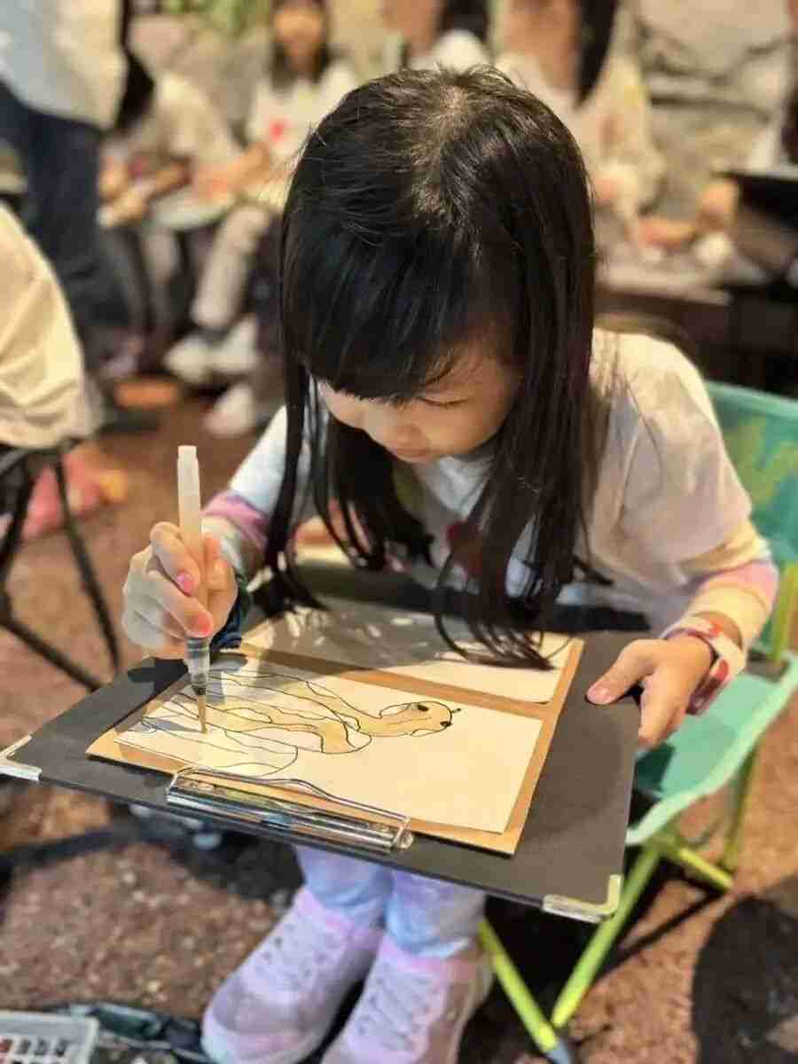 Children sketching together outdoors under a teacher's guidance