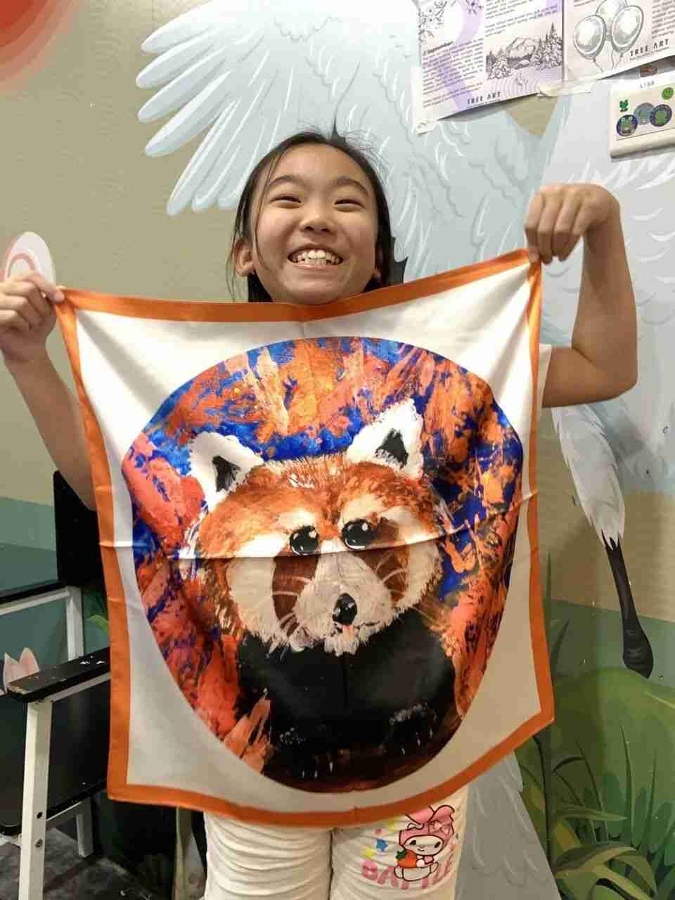 Young artist displaying a silk scarf featuring their own artwork