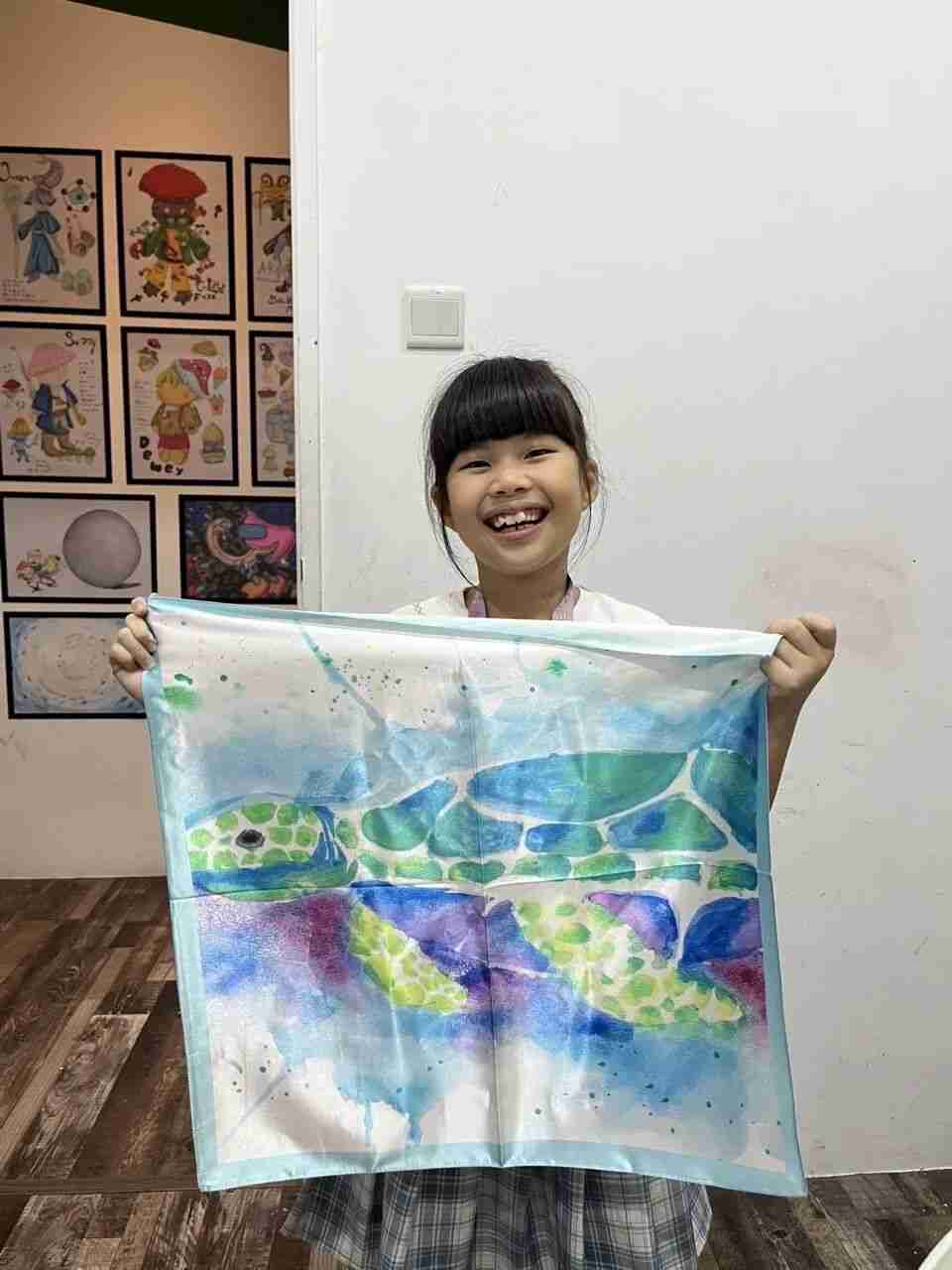 Young designer holding their hand-painted silk scarf