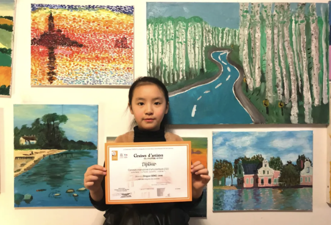 A young winner holding her diploma certificate in front of exhibited landscape paintings