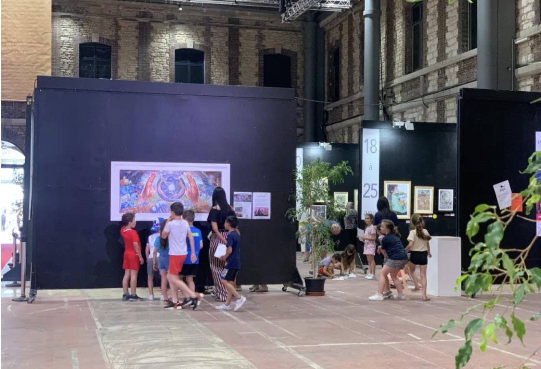 Visitors and children viewing framed artworks displayed at the international exhibition hall