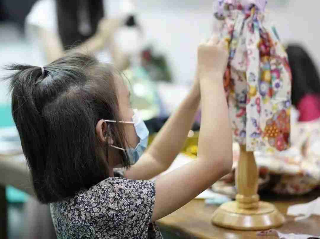 A TreeArt student dressing a small mannequin with a floral fabric design in Fashion Design class