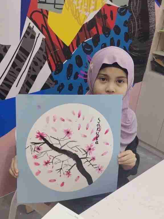 A TreeArt student holding up her cherry blossom (sakura) painting