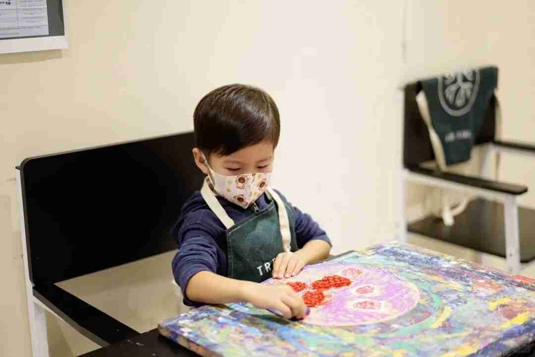 A boy in a TreeArt apron using his fingers to add texture to a colourful abstract painting