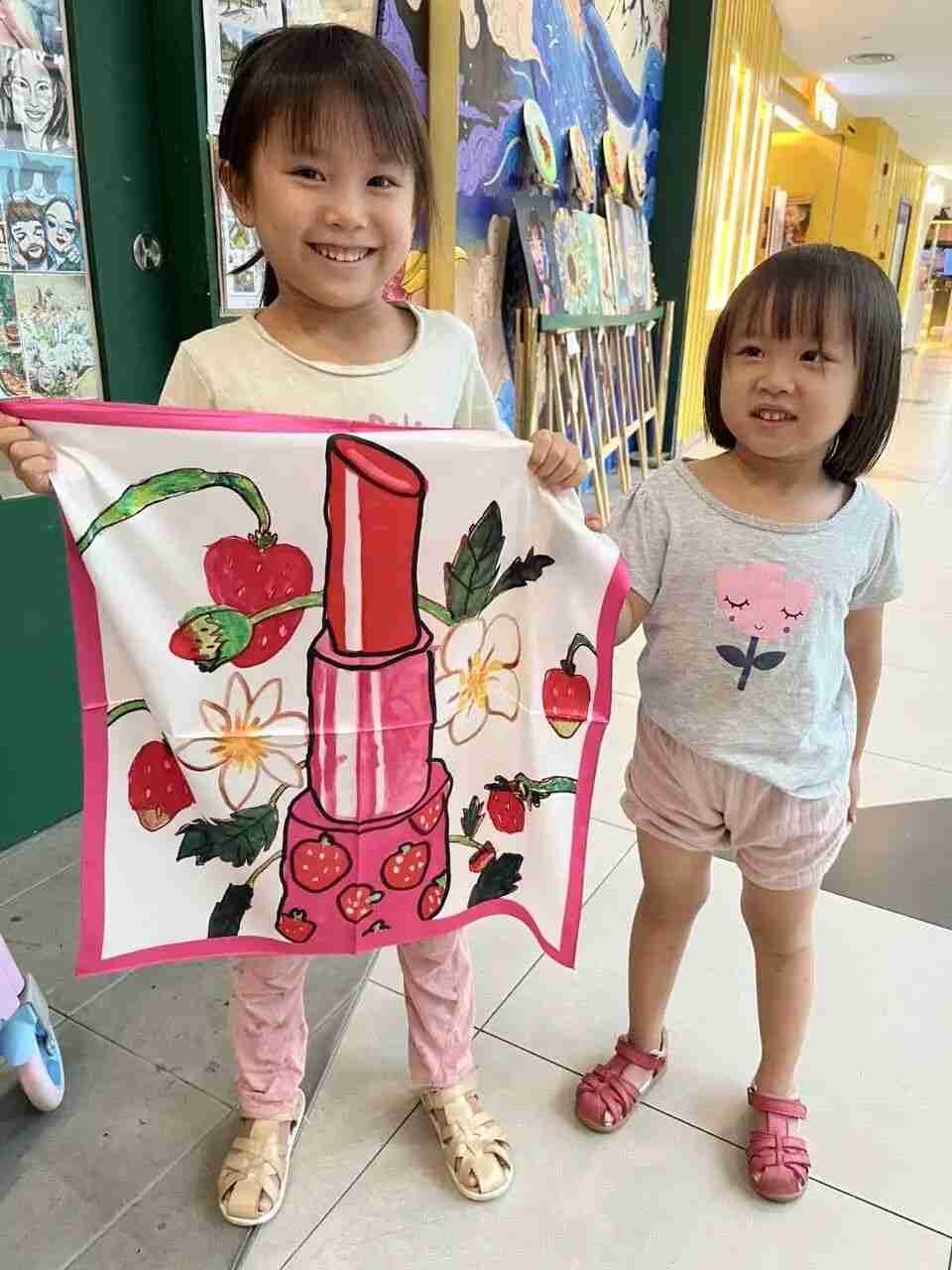 Child joyfully holding up their finished silk scarf design