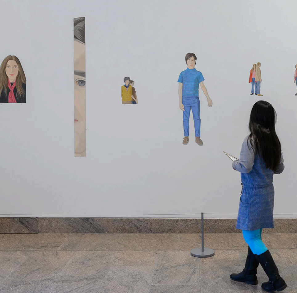 A visitor viewing children's portrait artworks displayed on a gallery wall