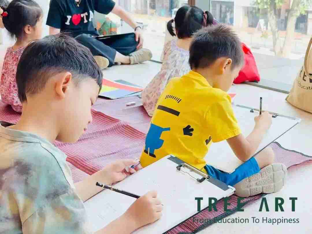 A group of children sitting on the floor sketching on clipboards during a TreeArt class