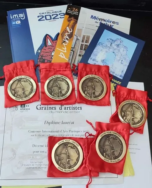 Gold medals from the Centre pour l'UNESCO Louis Francois in red pouches, displayed with the IMAJ competition catalogue and a laureate diploma