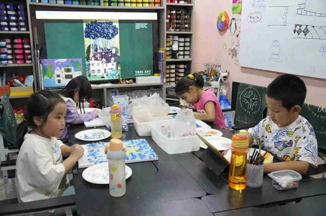 A group of children painting mosaic-style artwork together at a TreeArt studio table