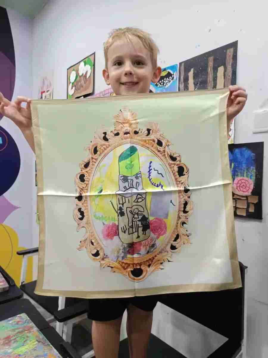 Child holding a hand-painted silk scarf created in the TREE ART course
