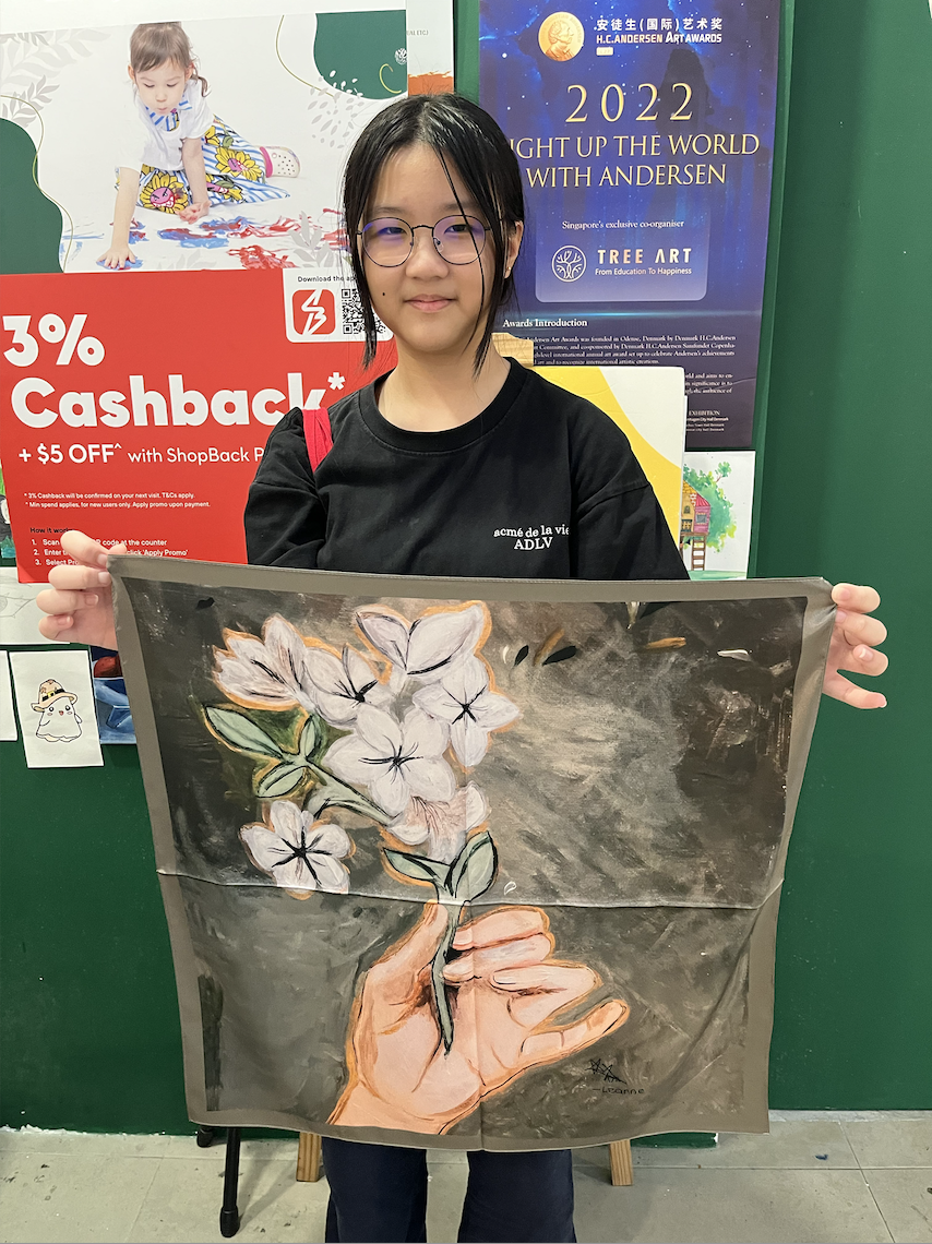 Close-up of a child's hands painting a silk scarf design