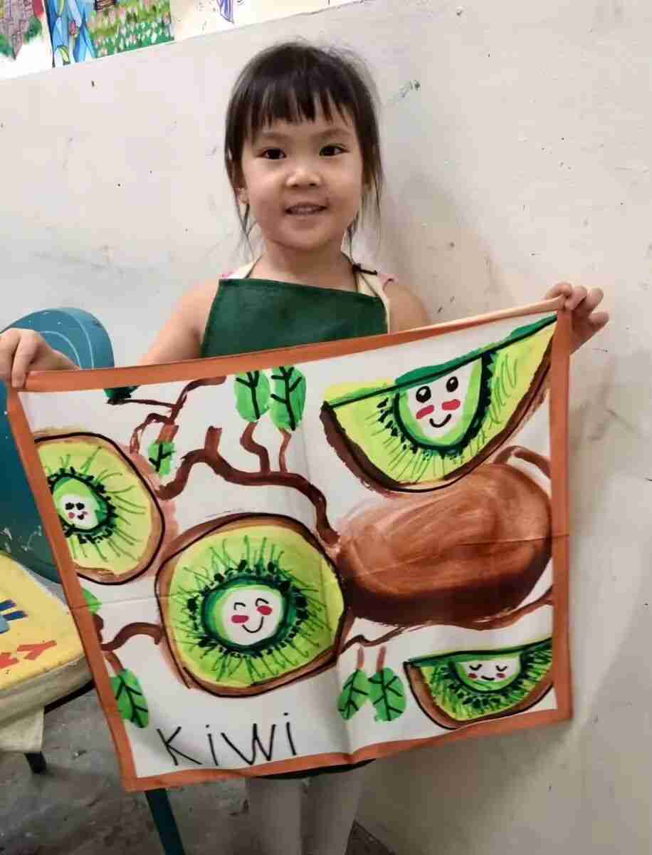 Child proudly showing a silk scarf painted with their own design