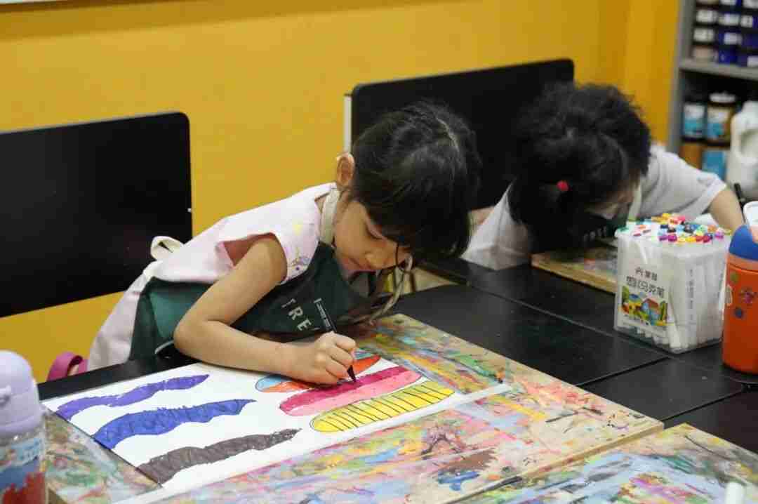 Two young girls concentrating as they paint at a table in a TreeArt art studio classroom