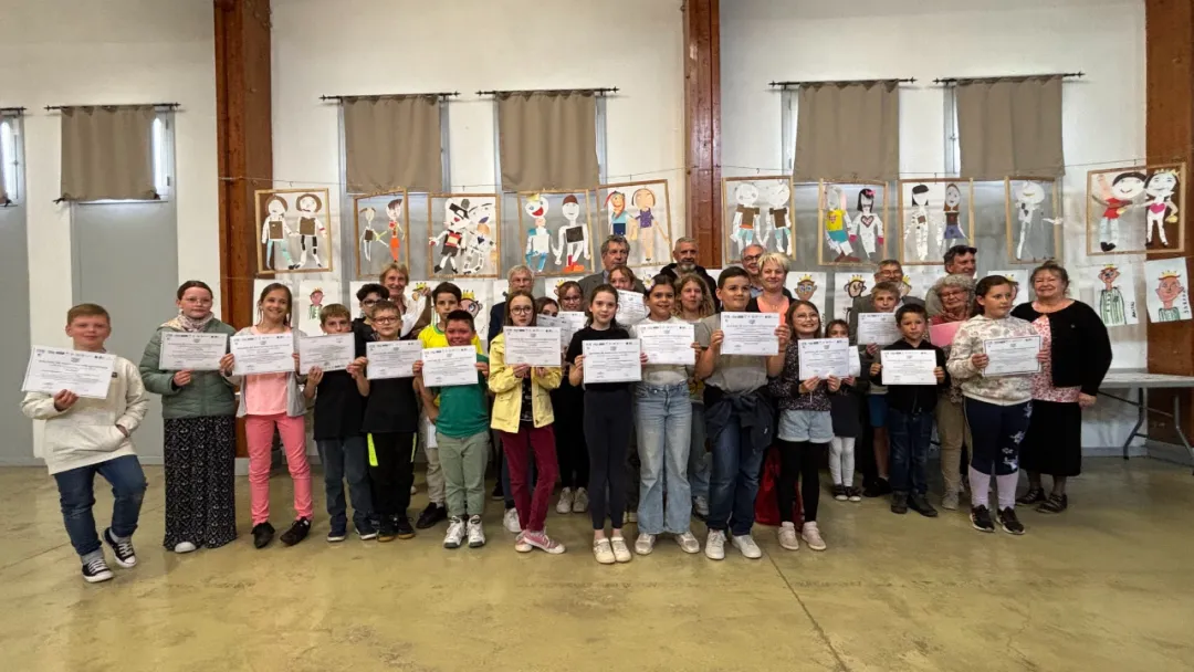 Group of child award winners holding their certificates in front of their exhibited artworks at the award ceremony